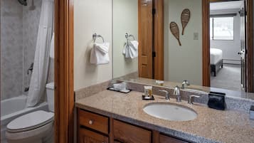 Un baño con ducha, inodoro, lavamanos y tocador.