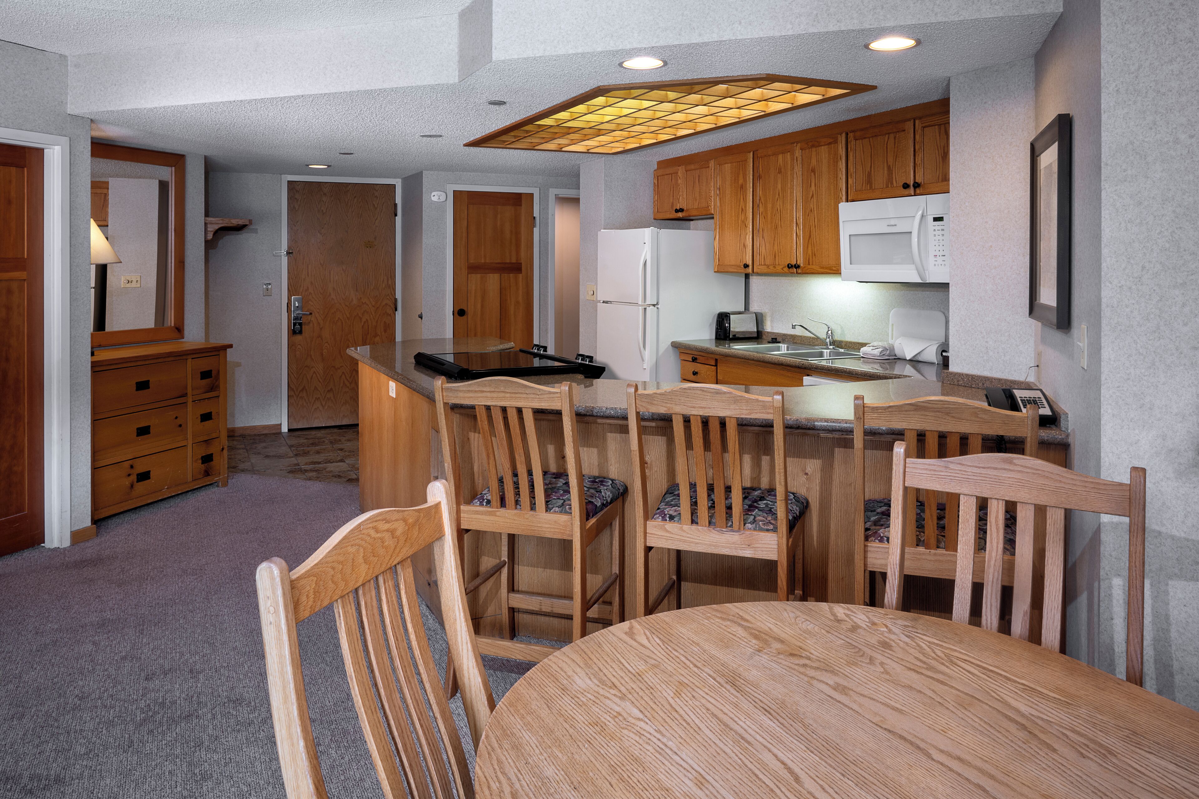 A compact kitchen with wooden cabinets, a microwave, and a refrigerator.