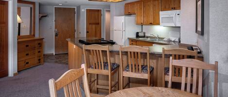 A compact kitchen with wooden cabinets, a microwave, and a refrigerator.