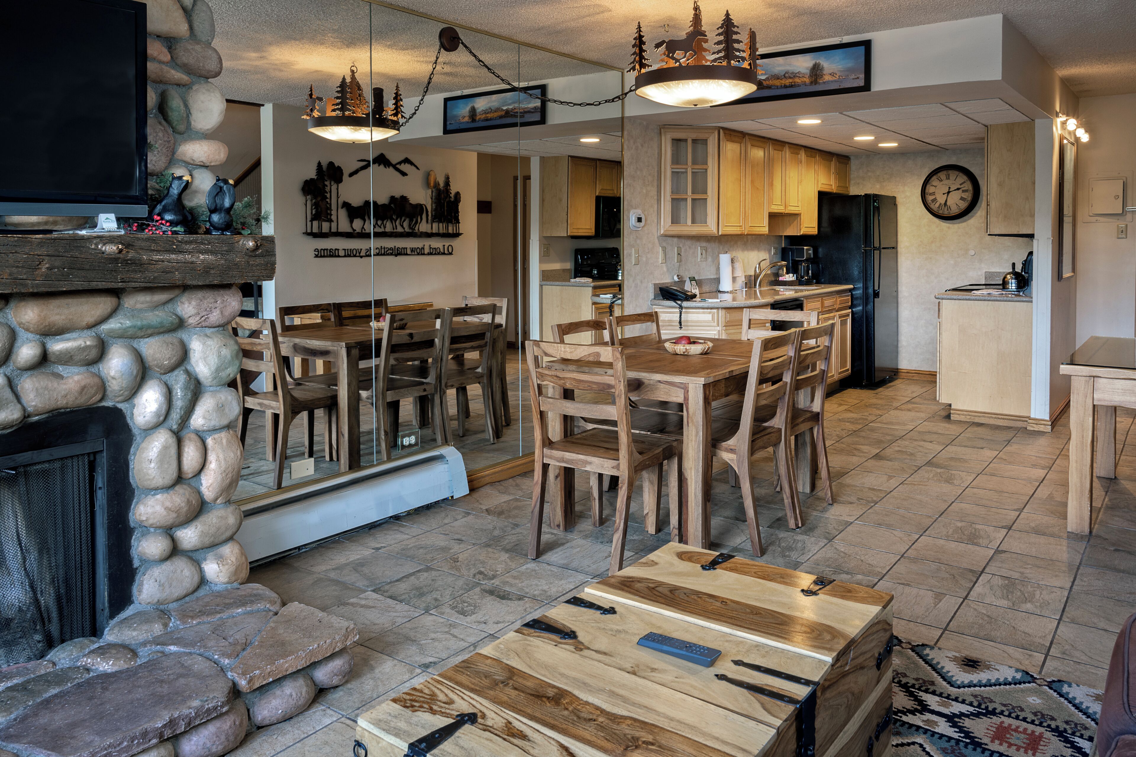A modern kitchen with wooden cabinets, a black refrigerator, and a dining area with a wooden table and chairs.