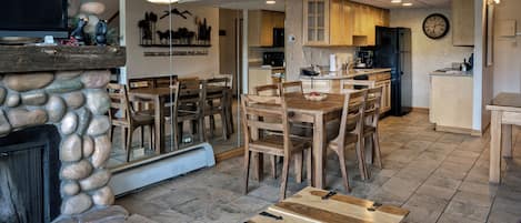 A modern kitchen with wooden cabinets, a black refrigerator, and a dining area with a wooden table and chairs.