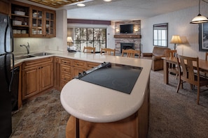 A kitchen with wooden cabinets, a built-in stove, a dining area with a table and chairs, and a fireplace.