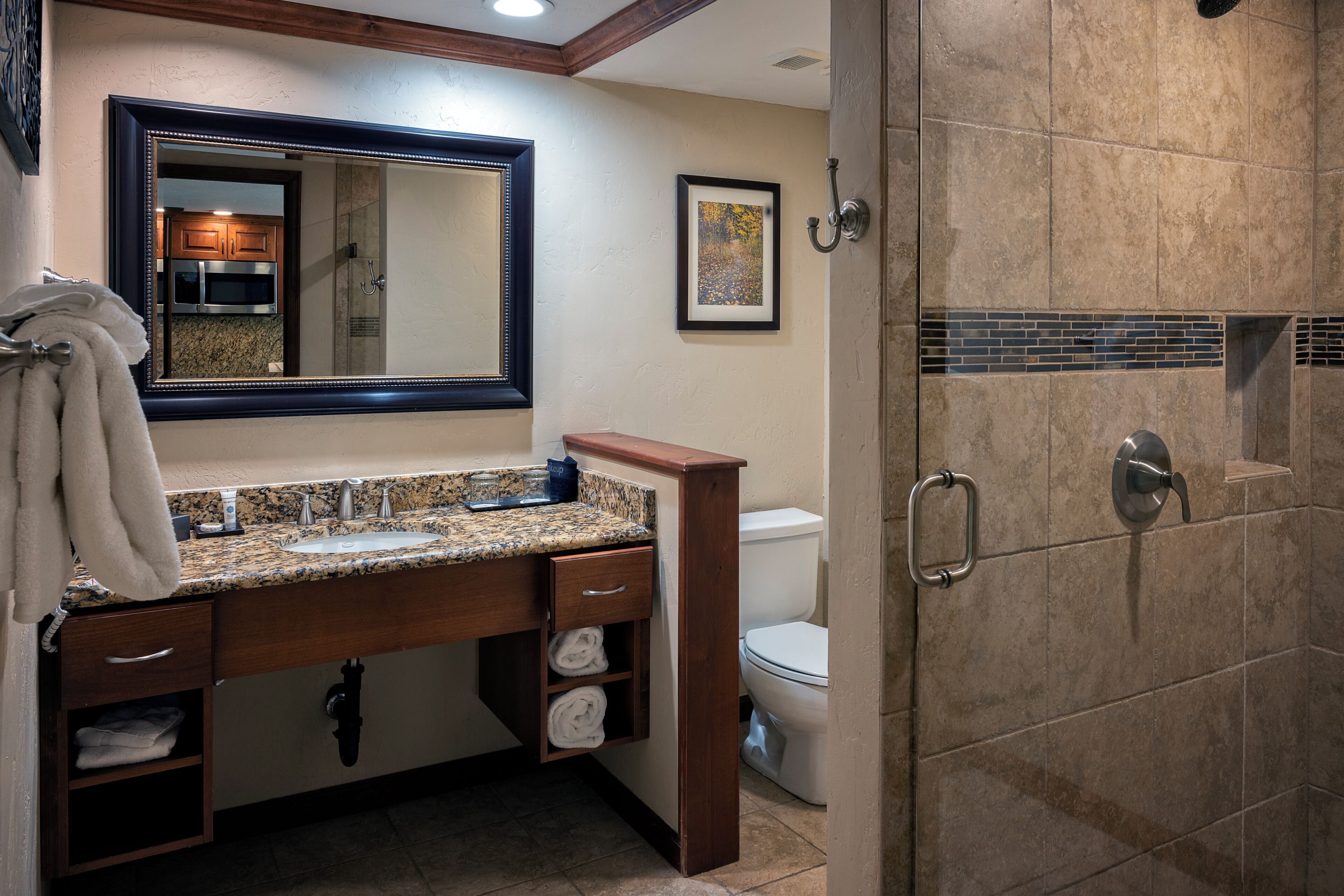 Baño con lavamanos de encimera de granito, mueble de madera y un inodoro.