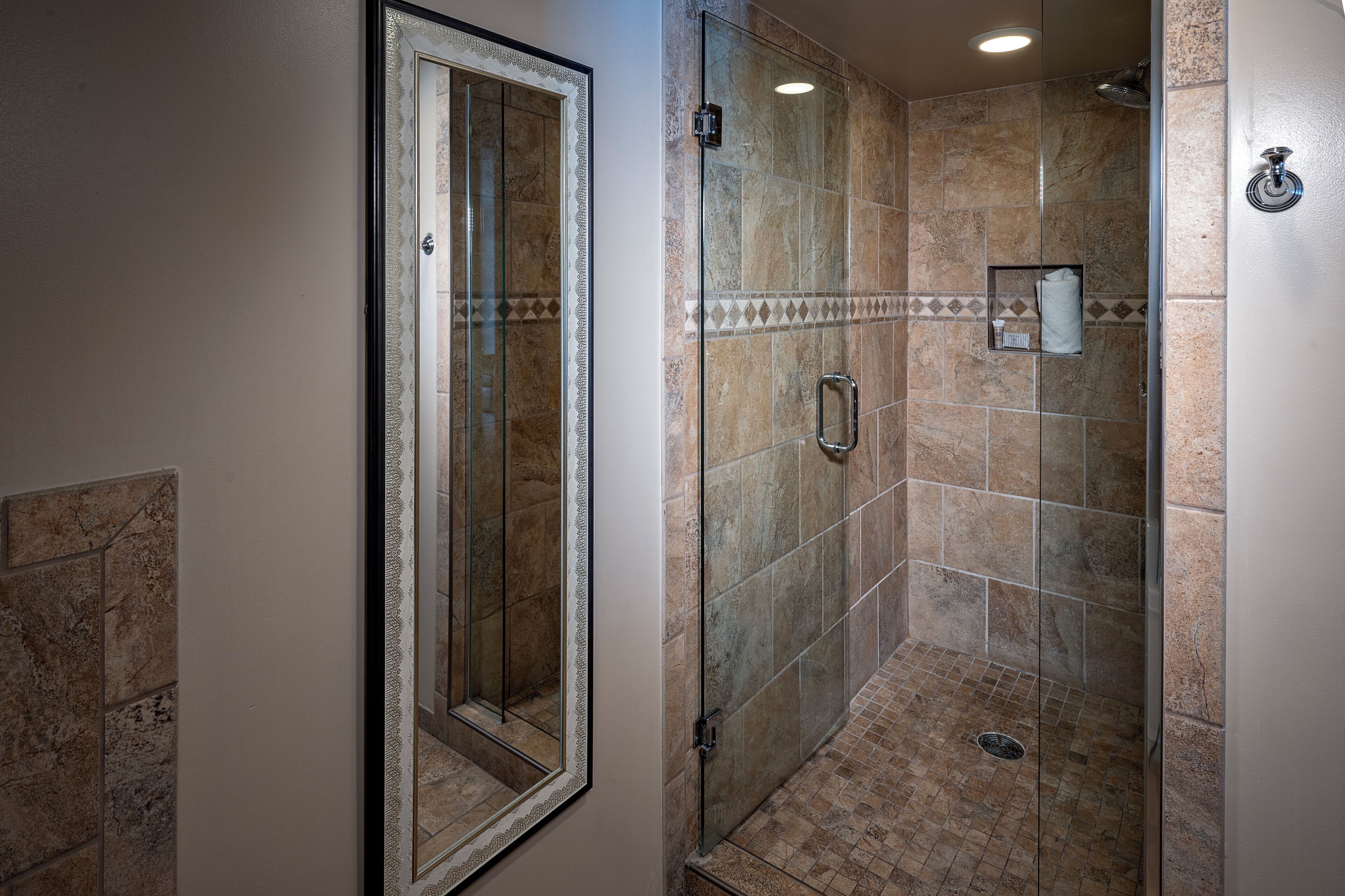 Une salle de bain avec une douche à parois de verre, un miroir et un porte-serviettes.