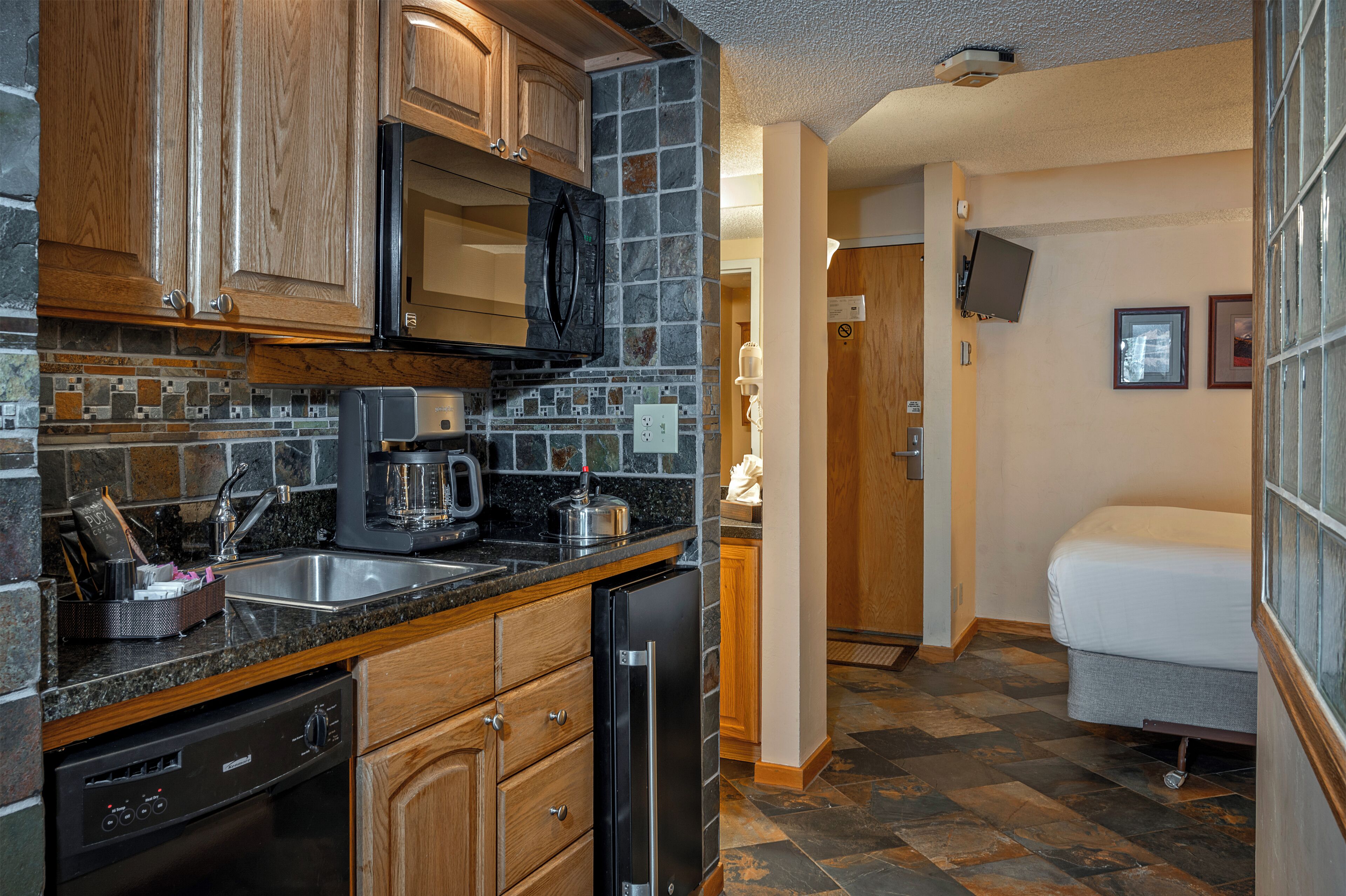 A compact kitchen with wooden cabinets, a microwave, and a coffee maker.