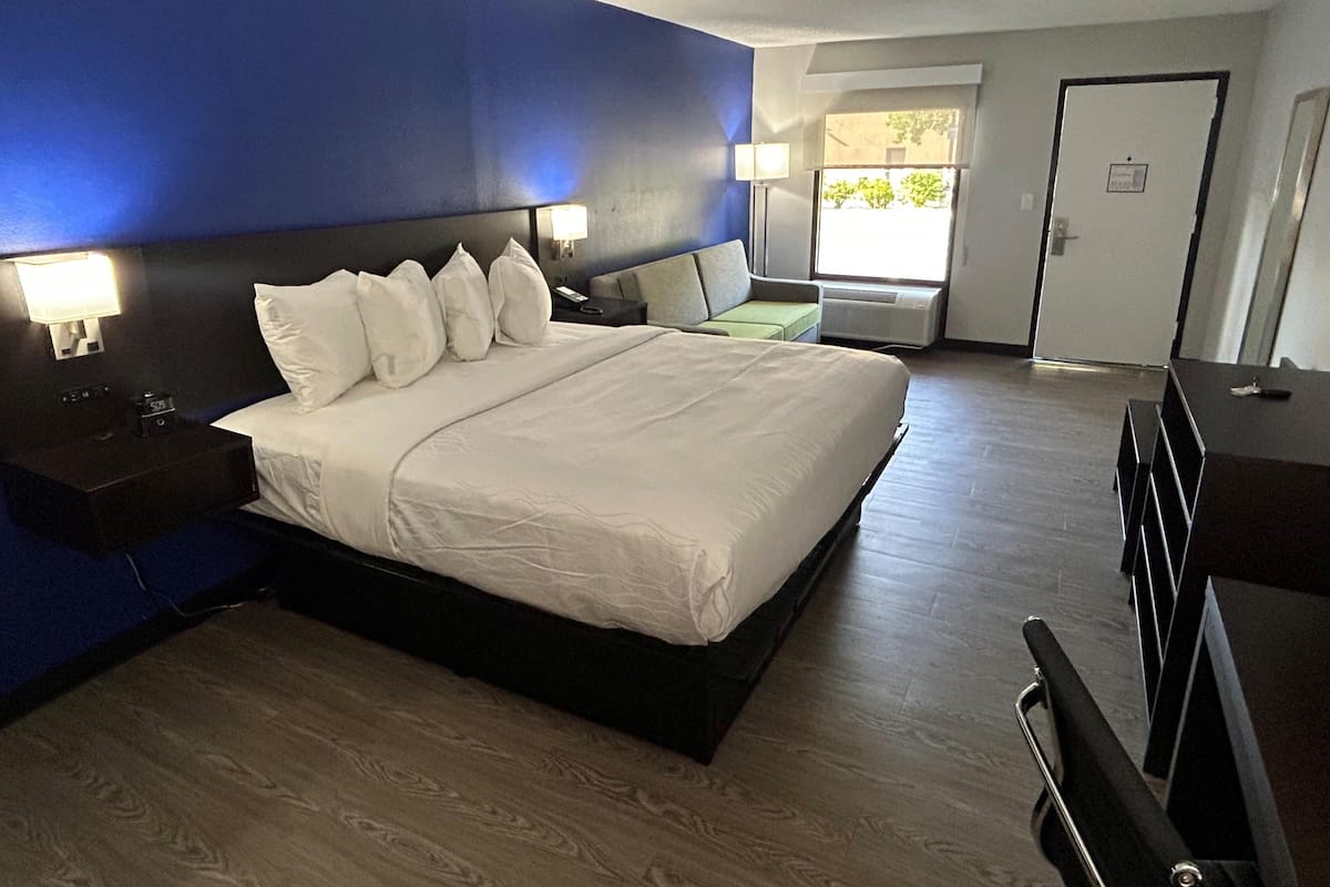 A hotel room with a large bed, bedside lamps, a desk, and a view of the outdoors.