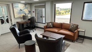 A modern interior with a leather sofa, two armchairs, a small table, and a desk with a computer. - SureStay Studio by Best Western Rowland (Rowland)