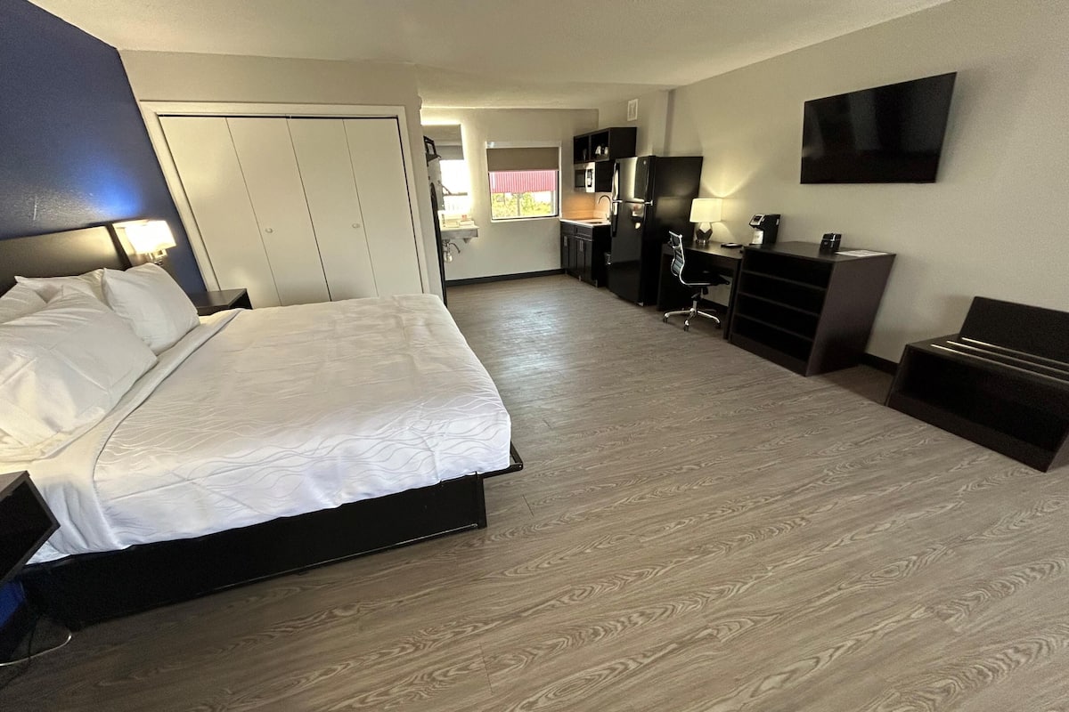 A hotel room with a bed, a desk, a TV, and a wardrobe.