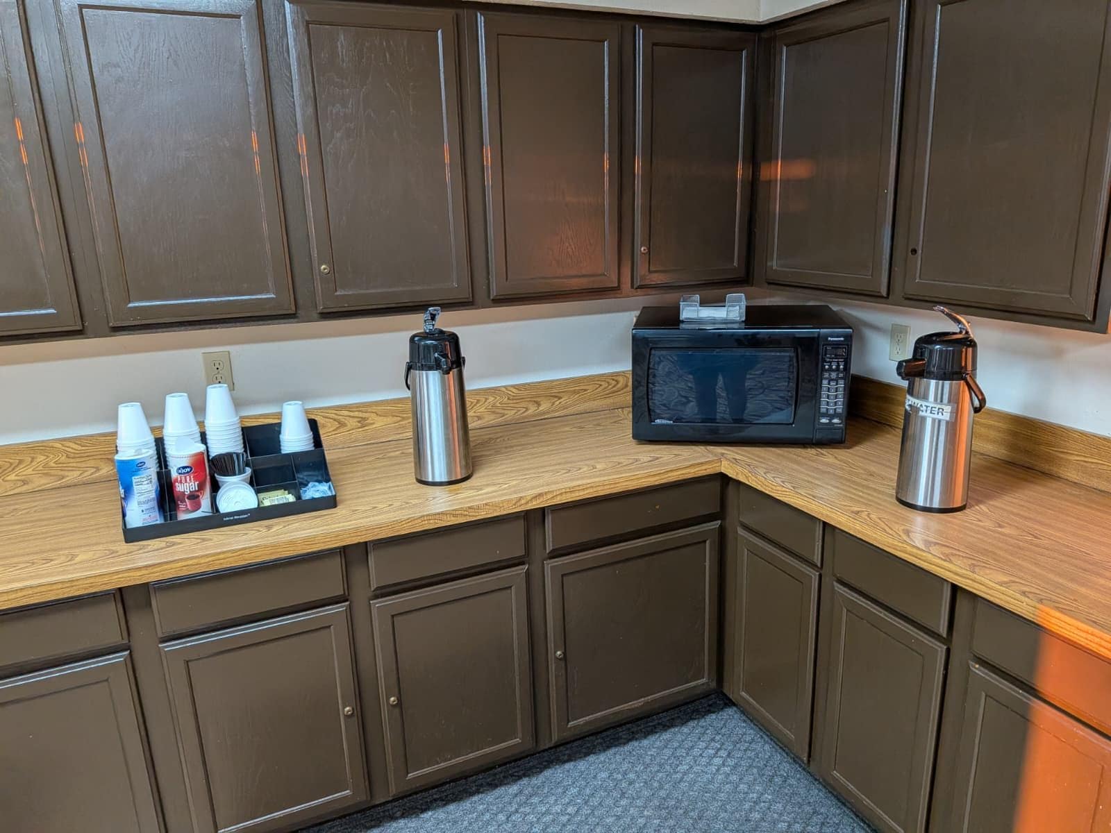 A kitchenette with a microwave, a coffee maker, and a water bottle on the counter.