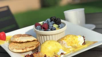 A breakfast plate with eggs benedict, berries, and pancakes.