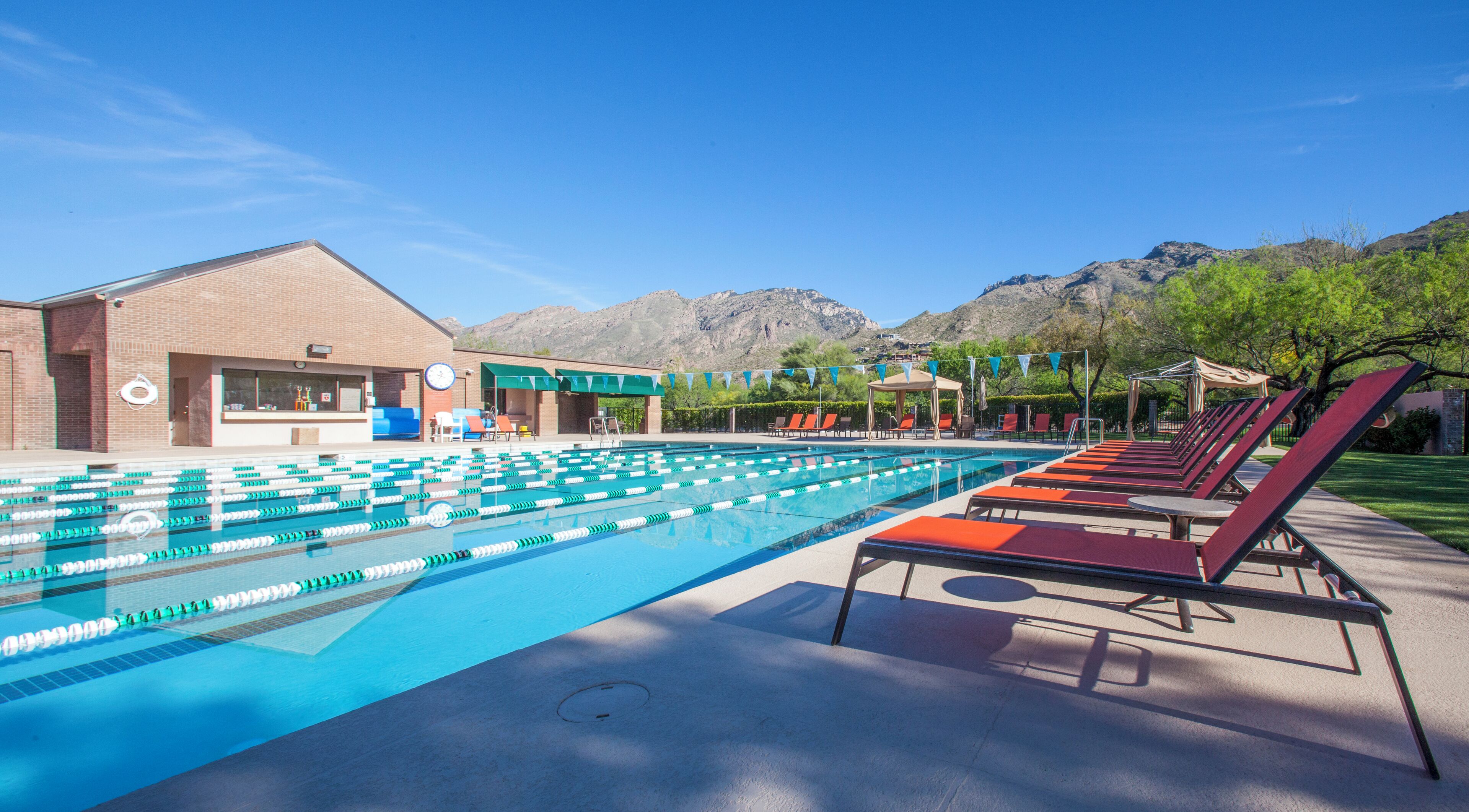 Una piscina con corsie, sdraio e montagne sullo sfondo.