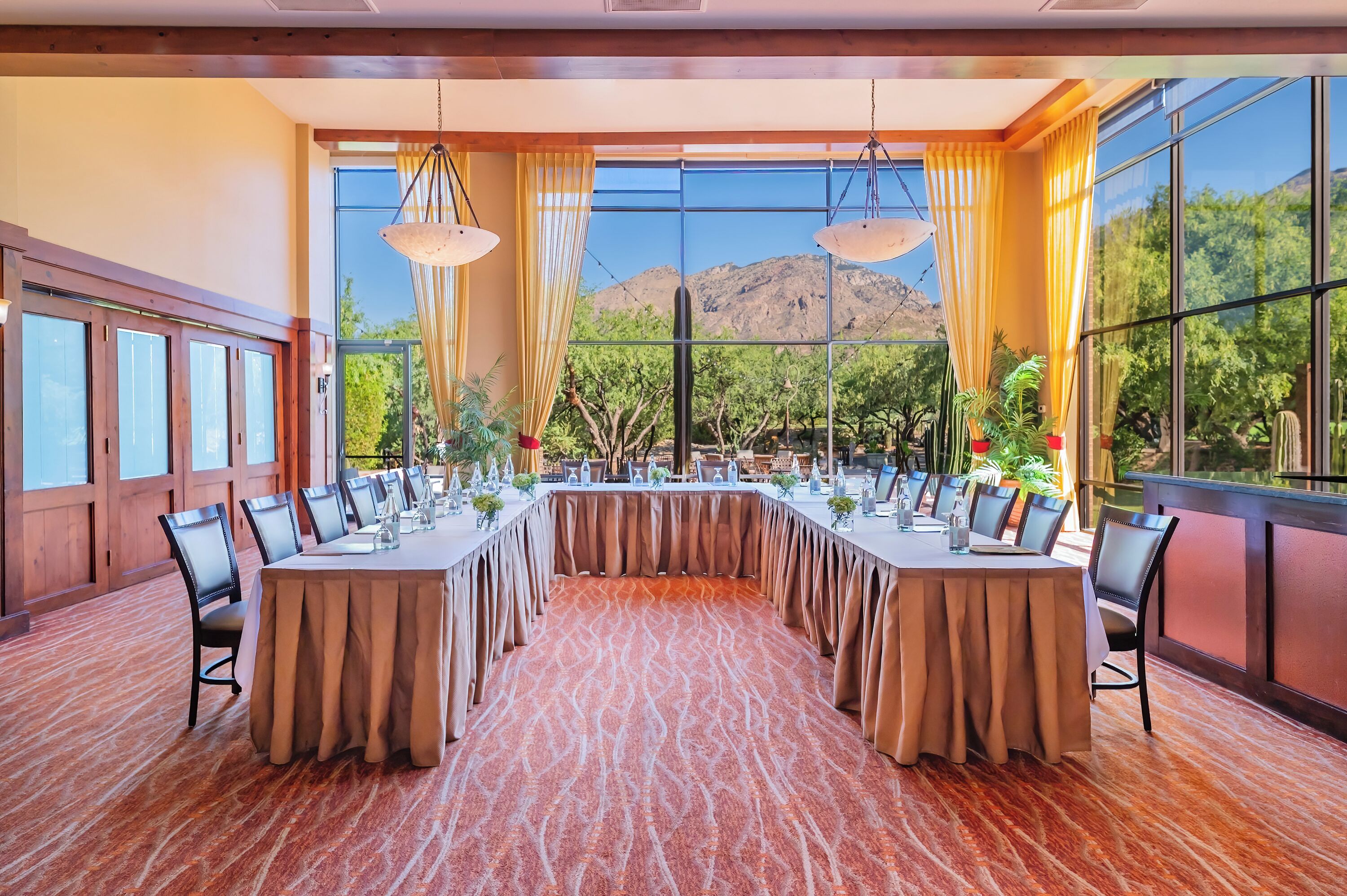 A conference room with a long table, chairs, and large windows with curtains.