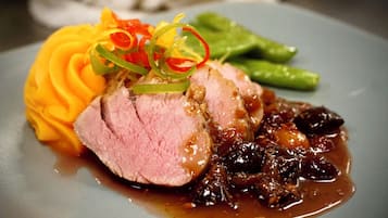 A plate with sliced meat, a side of mashed potatoes, and a dark sauce.
