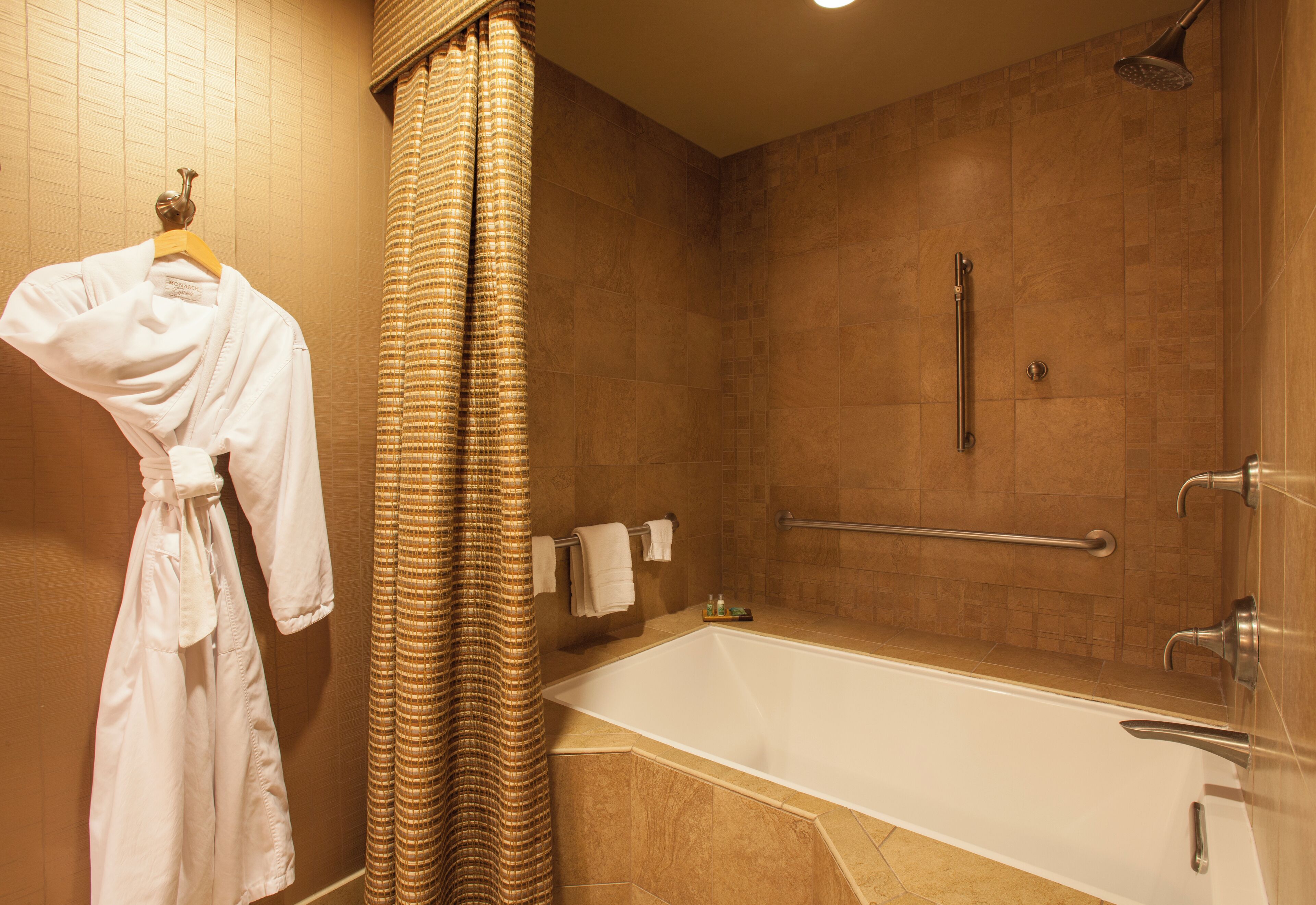Une salle de bain équipée d’une baignoire, d’une douche et d’un porte-serviettes avec des peignoirs.