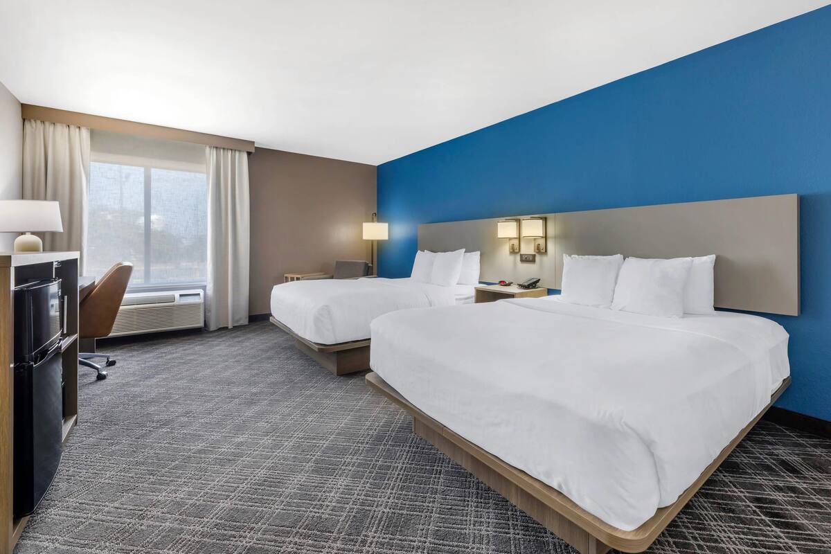 Een hotelkamer met twee bedden, een bureau en een stoel.