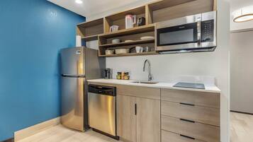 Una cocina moderna con refrigerador de acero inoxidable, lavavajillas y microondas.