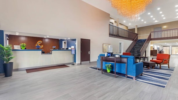 A spacious lobby with a reception desk, seating area, and a staircase leading to an upper level.