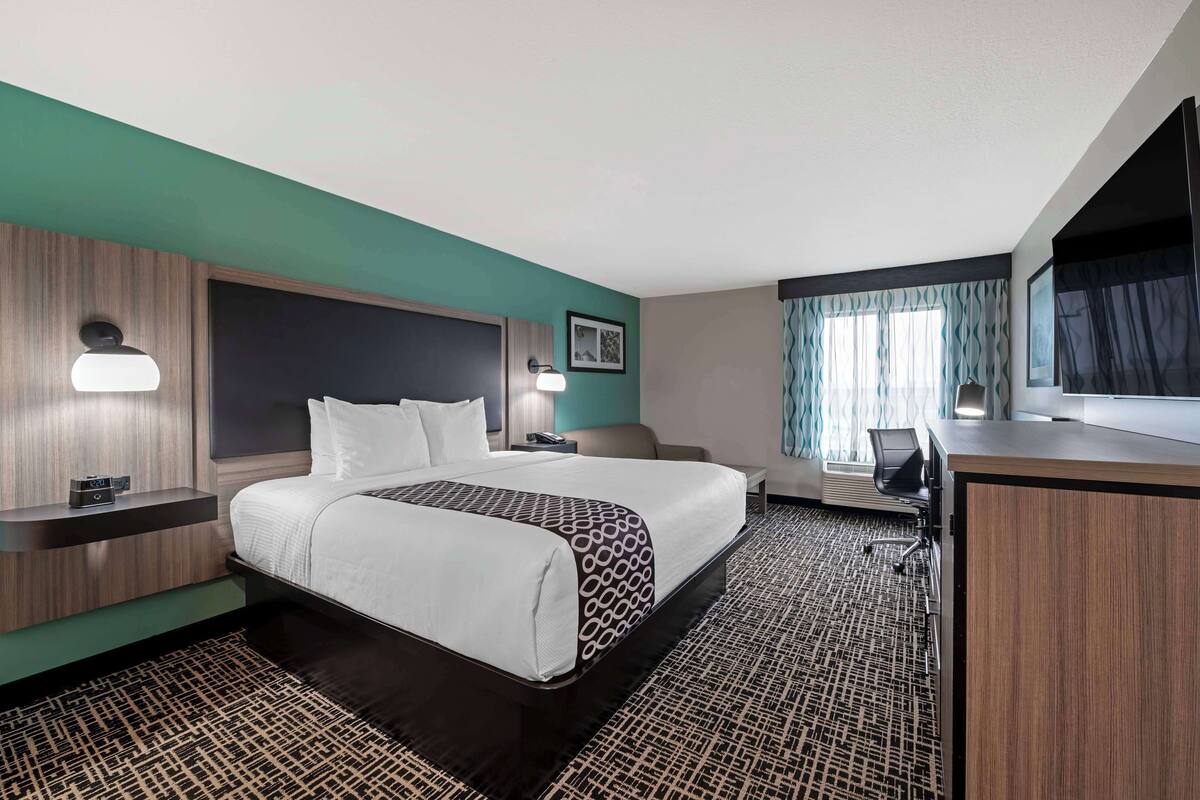 A hotel room with a large bed, a desk, a chair, and a television.