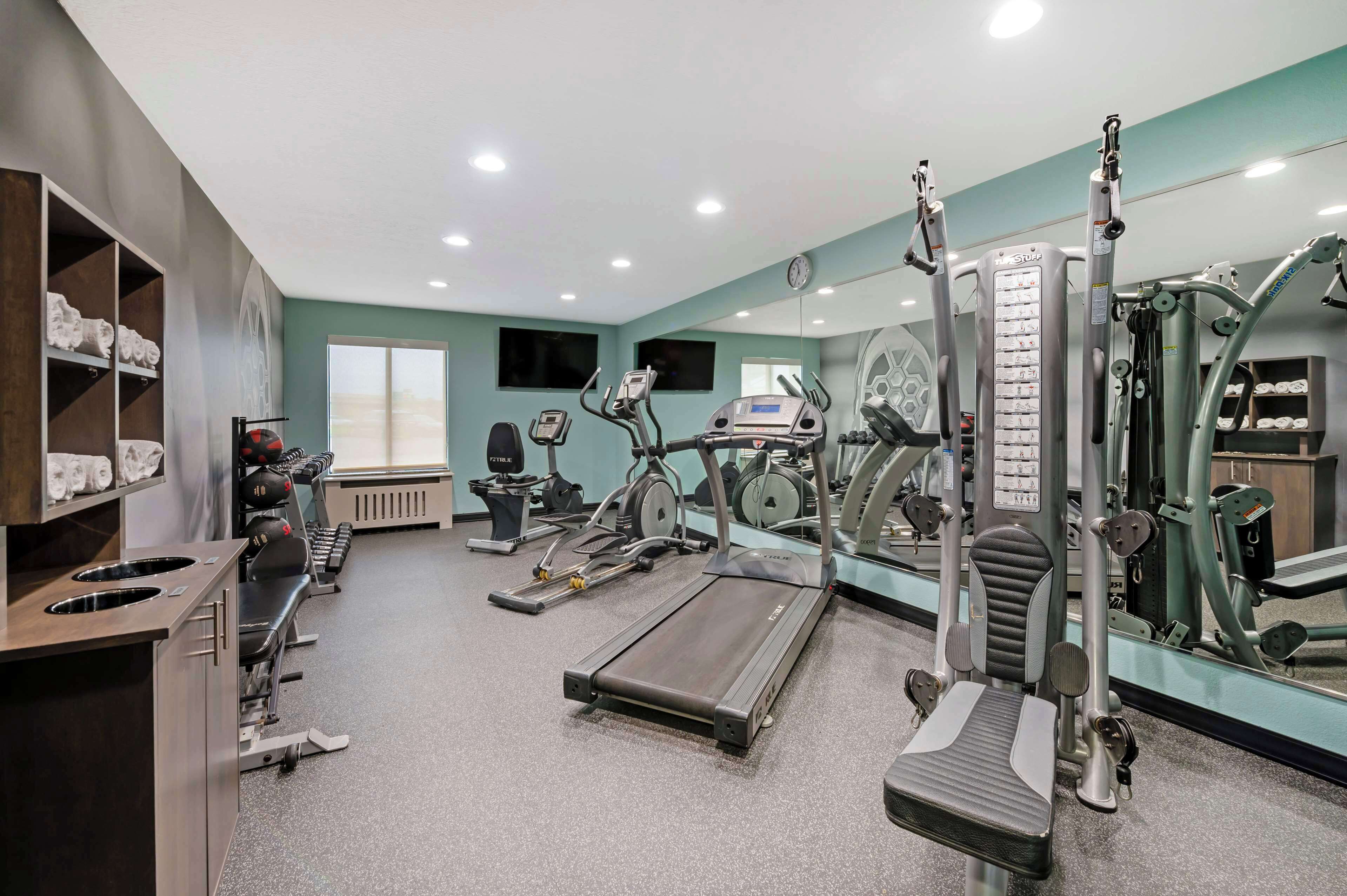 Un gimnasio con cintas de correr, elípticas y equipos de pesas.