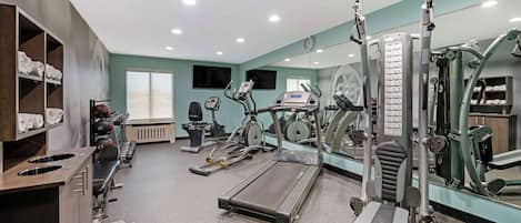 Un gimnasio con cintas de correr, elípticas y equipos de pesas.