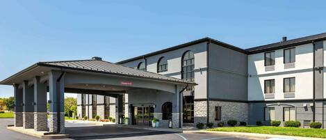 A modern hotel with a covered entrance, a parking lot, and a handicap parking space.