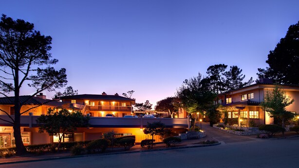 A two-story hotel with a balcony and a parking area.