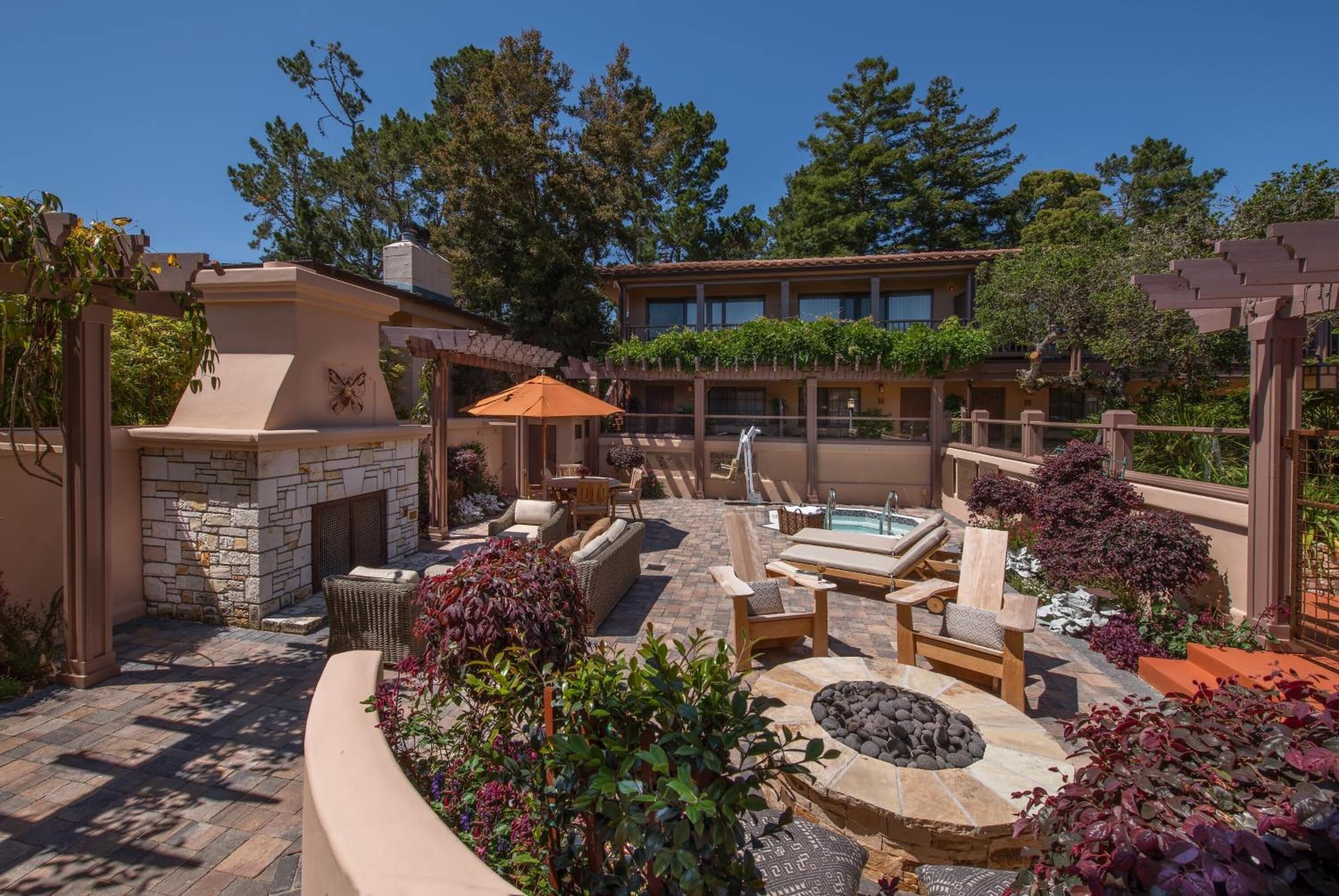 An outdoor patio with stone seating, a fire pit, and a pool area.