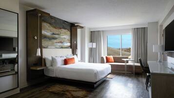 A modern hotel room with a large bed, a desk, a chair, and a television.