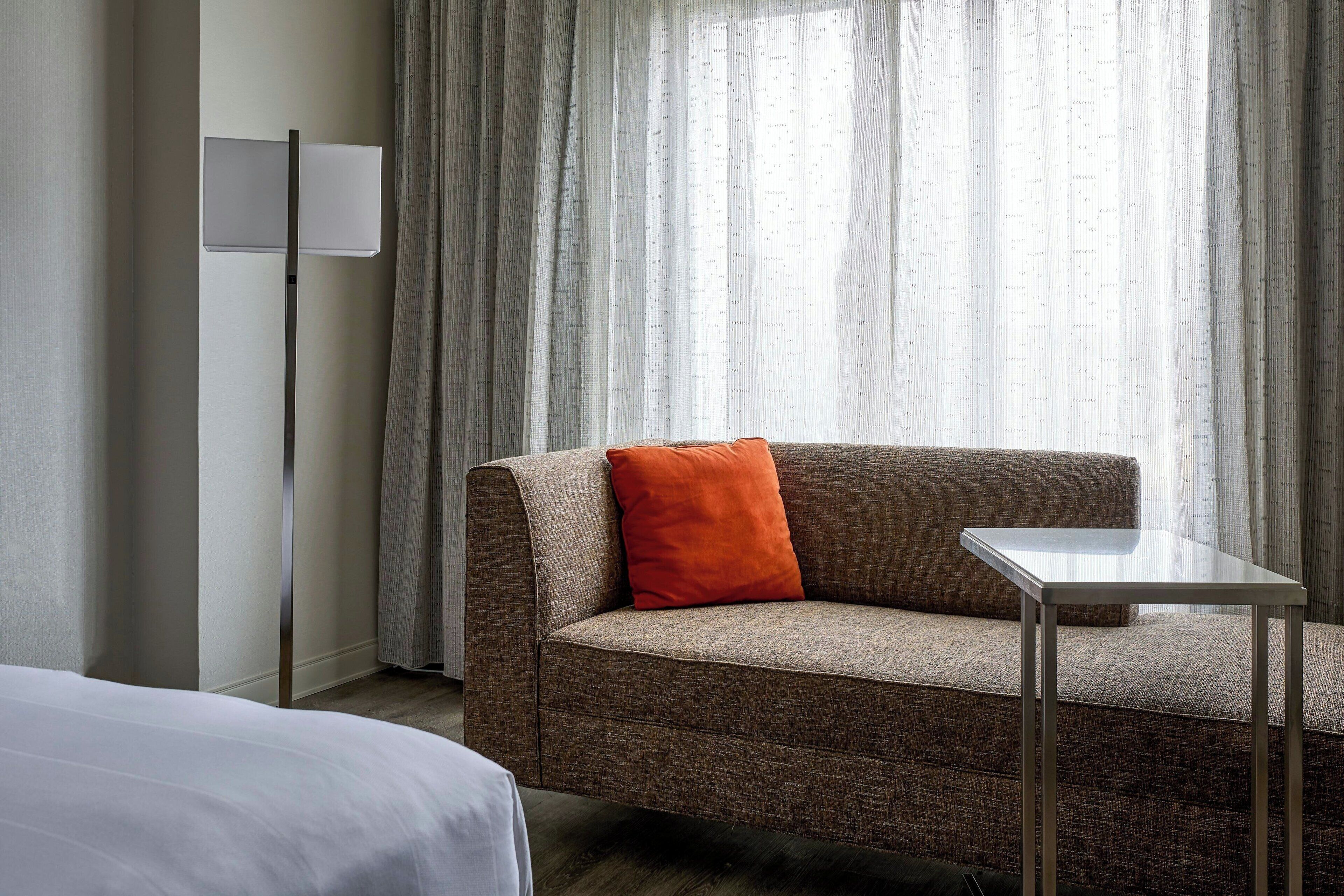 A hotel room with a sofa, a small table, and a bed.
