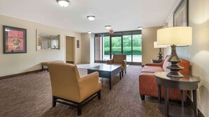 A hotel lobby with a reception desk, seating area, and large windows offering a view of greenery. - Extended Stay America Select Suites Atlanta Alpharetta Norpt (Alpharetta)