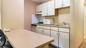 A compact kitchen with white cabinets, a microwave, a stove, and a sink. - Extended Stay America Select Suites Atlanta Alpharetta Norpt (Alpharetta)