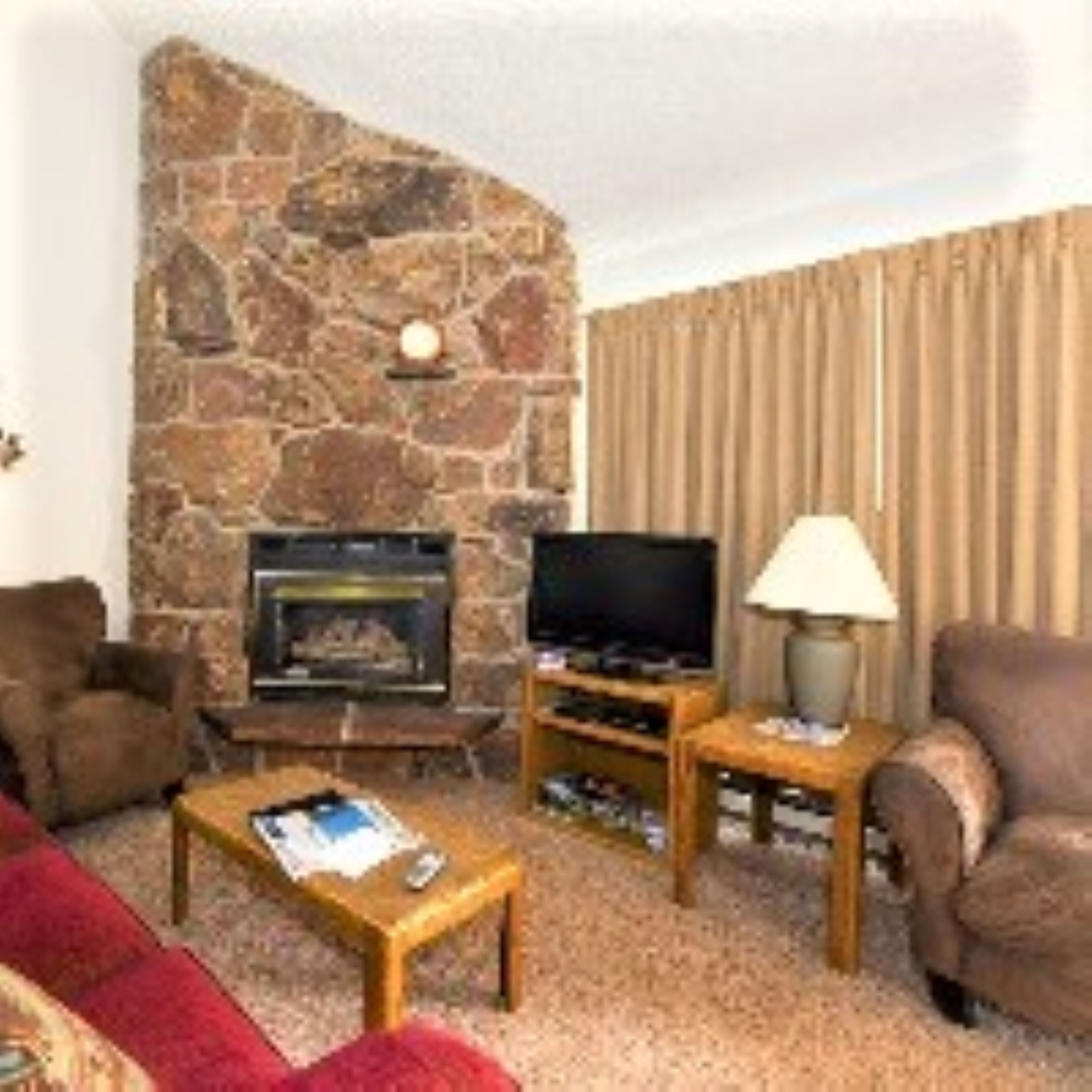 Una sala de estar con chimenea de piedra, un televisor y dos sillones.