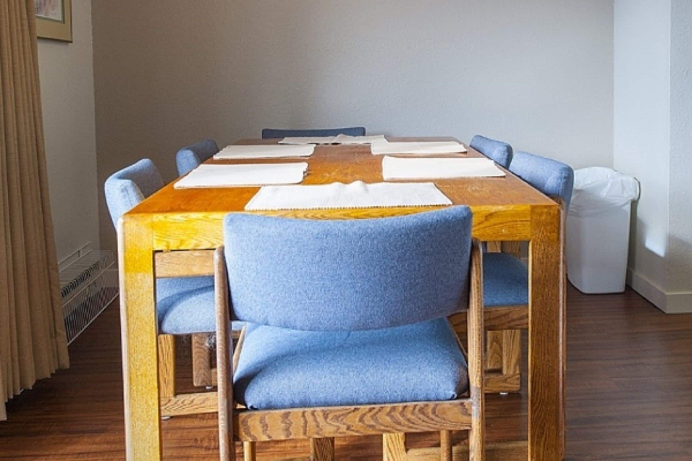 Un tavolo da pranzo con sei sedie, un piano tavolo in legno e sedute rivestite in blu.