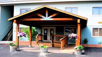 A building with a wooden porch, a staircase, and flower planters.