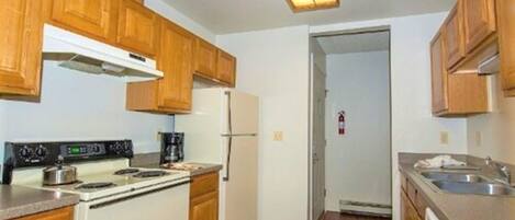 A compact kitchen with wooden cabinets, a white stove, and a refrigerator.