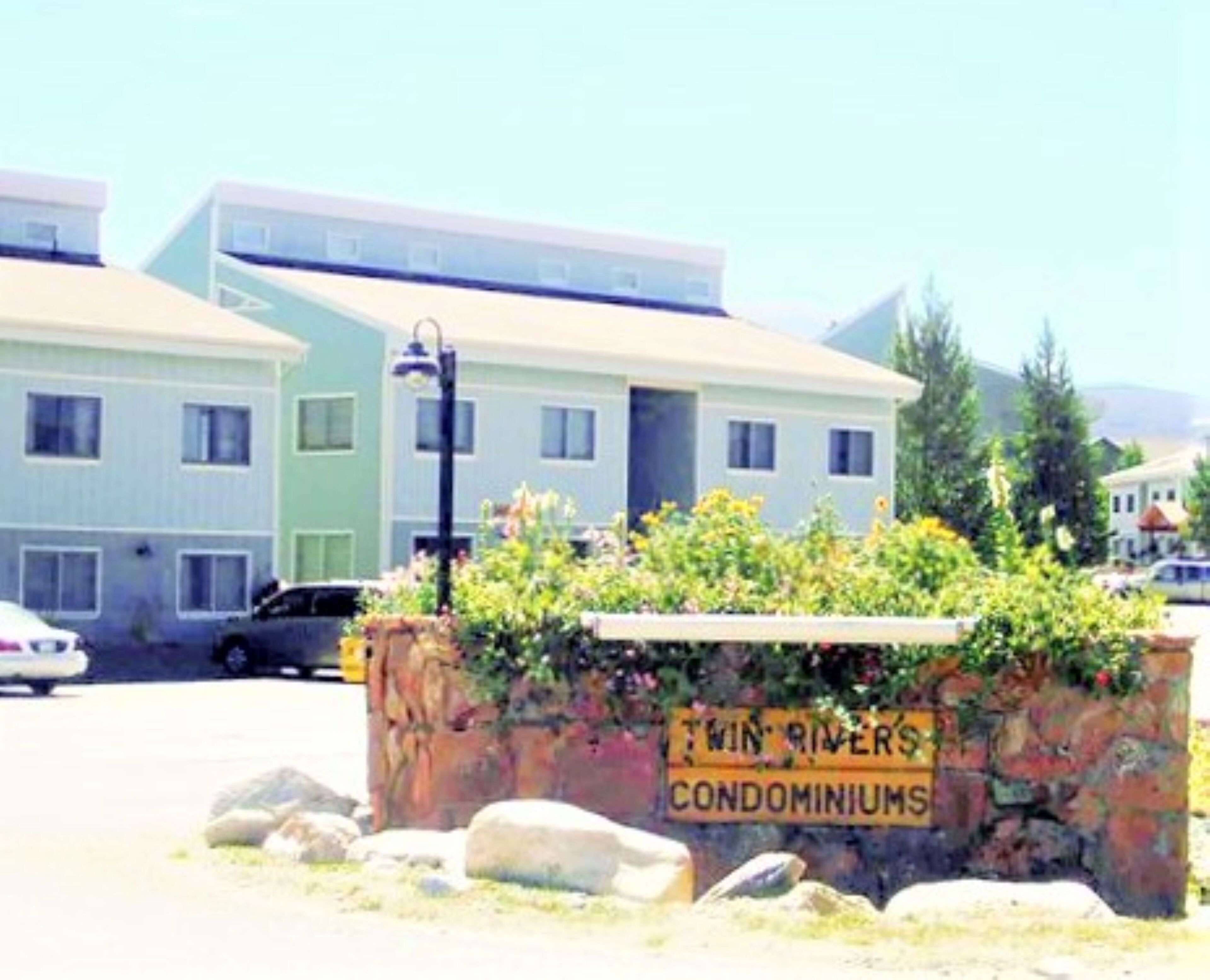 A sign for Twin Rivers Condominiums with a clear view of the building's exterior.