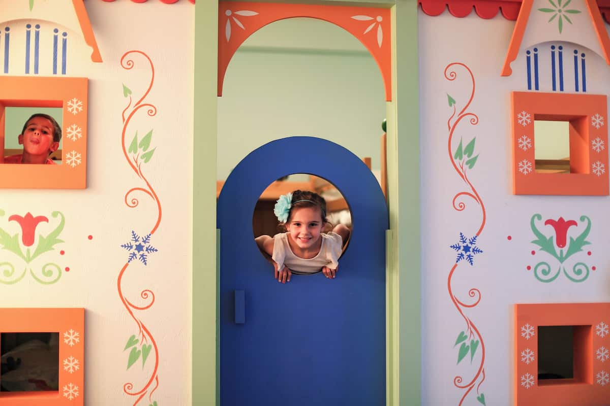 A child's playhouse with a circular window, decorative snowflakes, and a red and green color scheme.