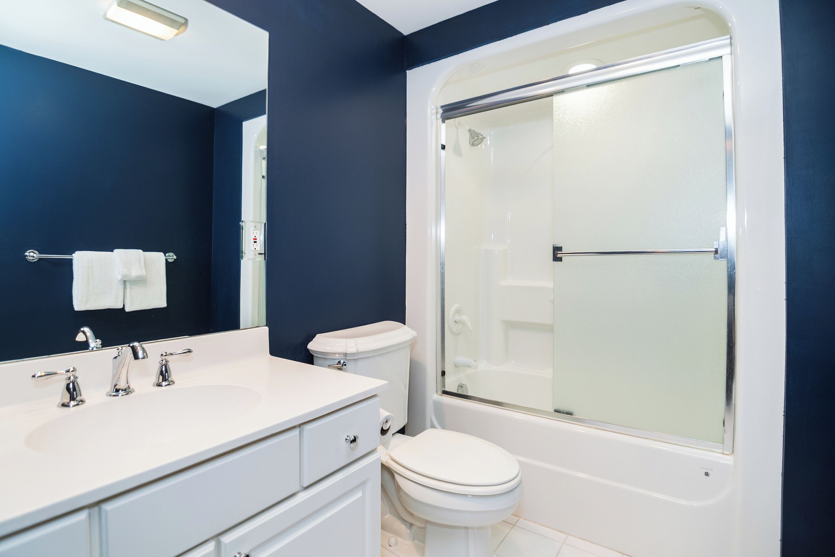 Un baño con lavamanos, inodoro y bañera blancos.