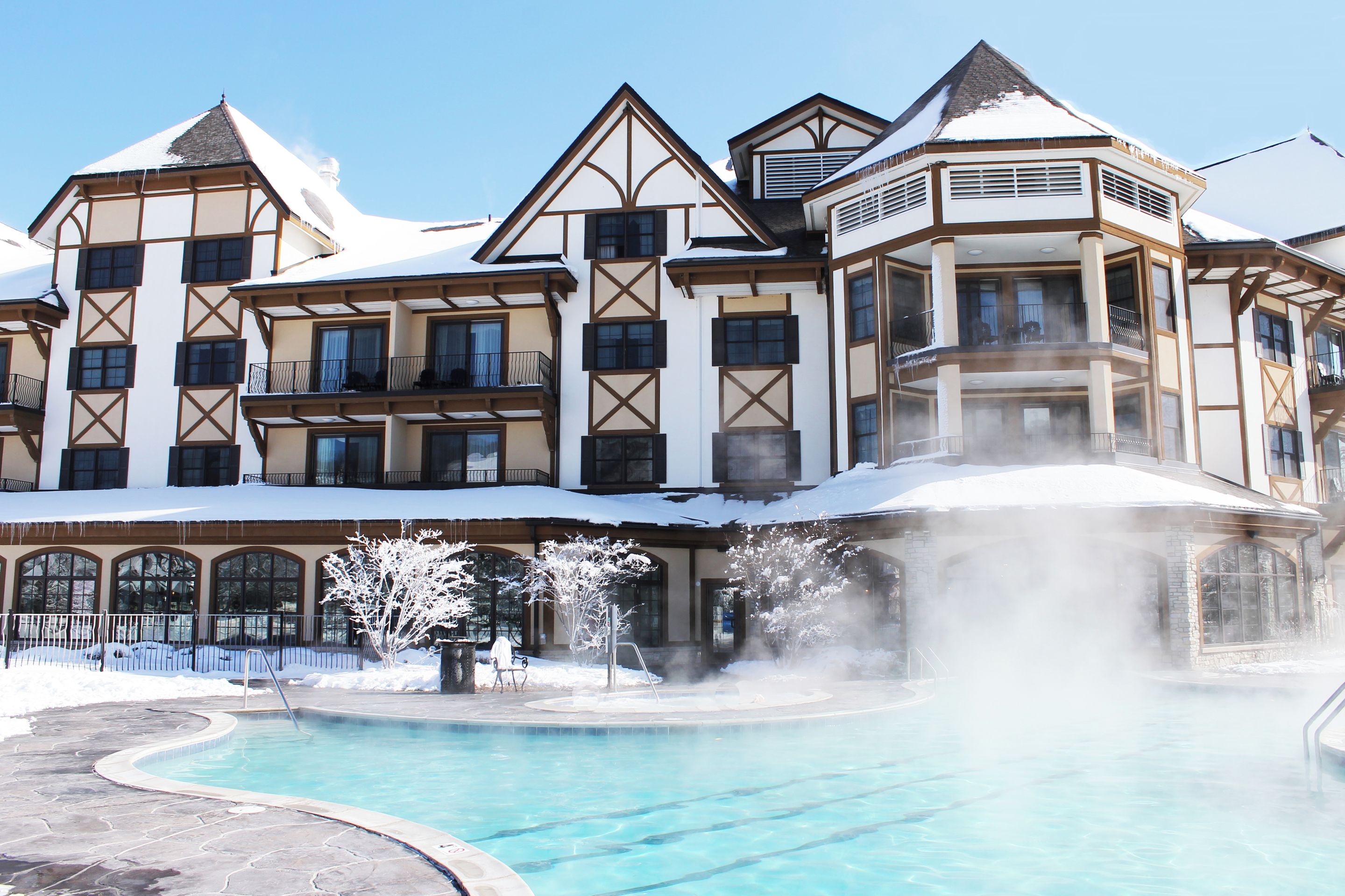 A large hotel with multiple balconies, a swimming pool, and a hot spring area.