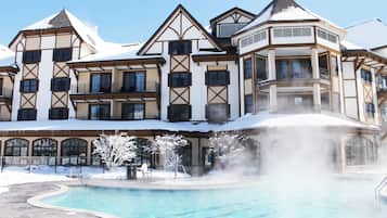A large hotel with multiple balconies, a swimming pool, and a hot spring area.