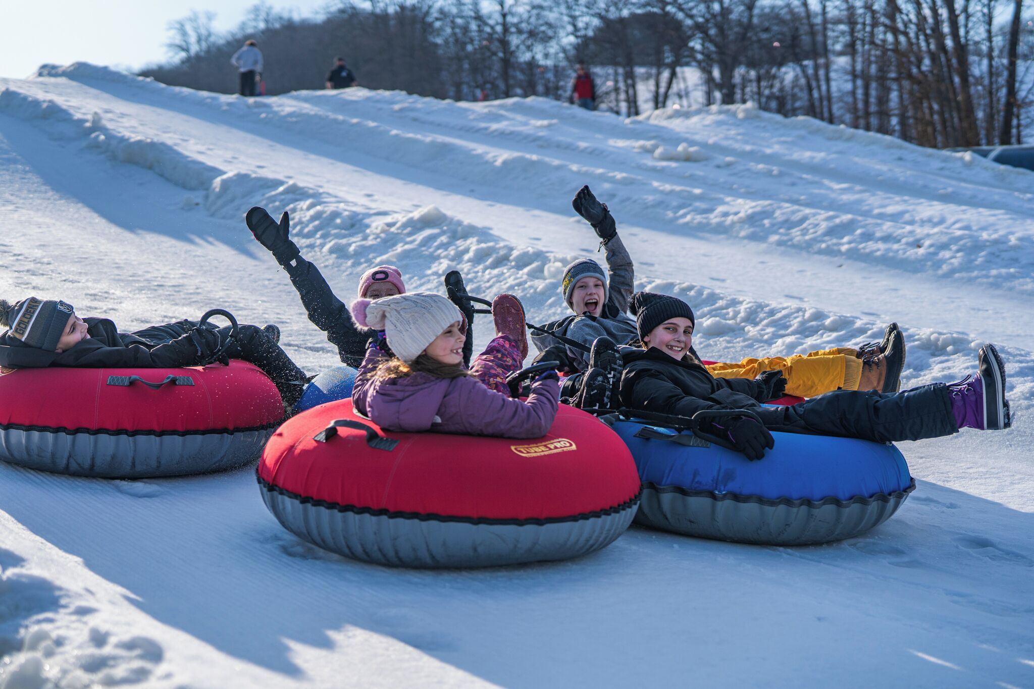 People riding snow tubes down a snowy slope.