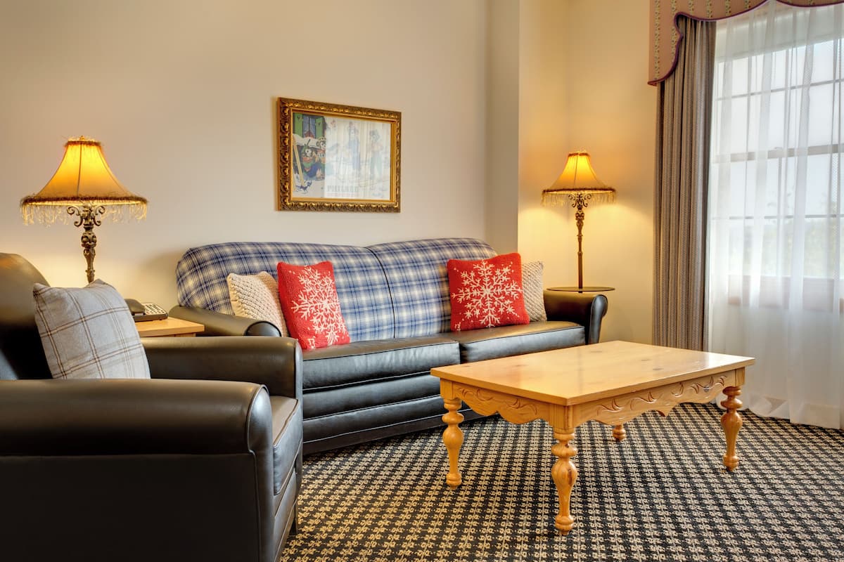 A living room with a sofa, two lamps, a table, and a patterned carpet.