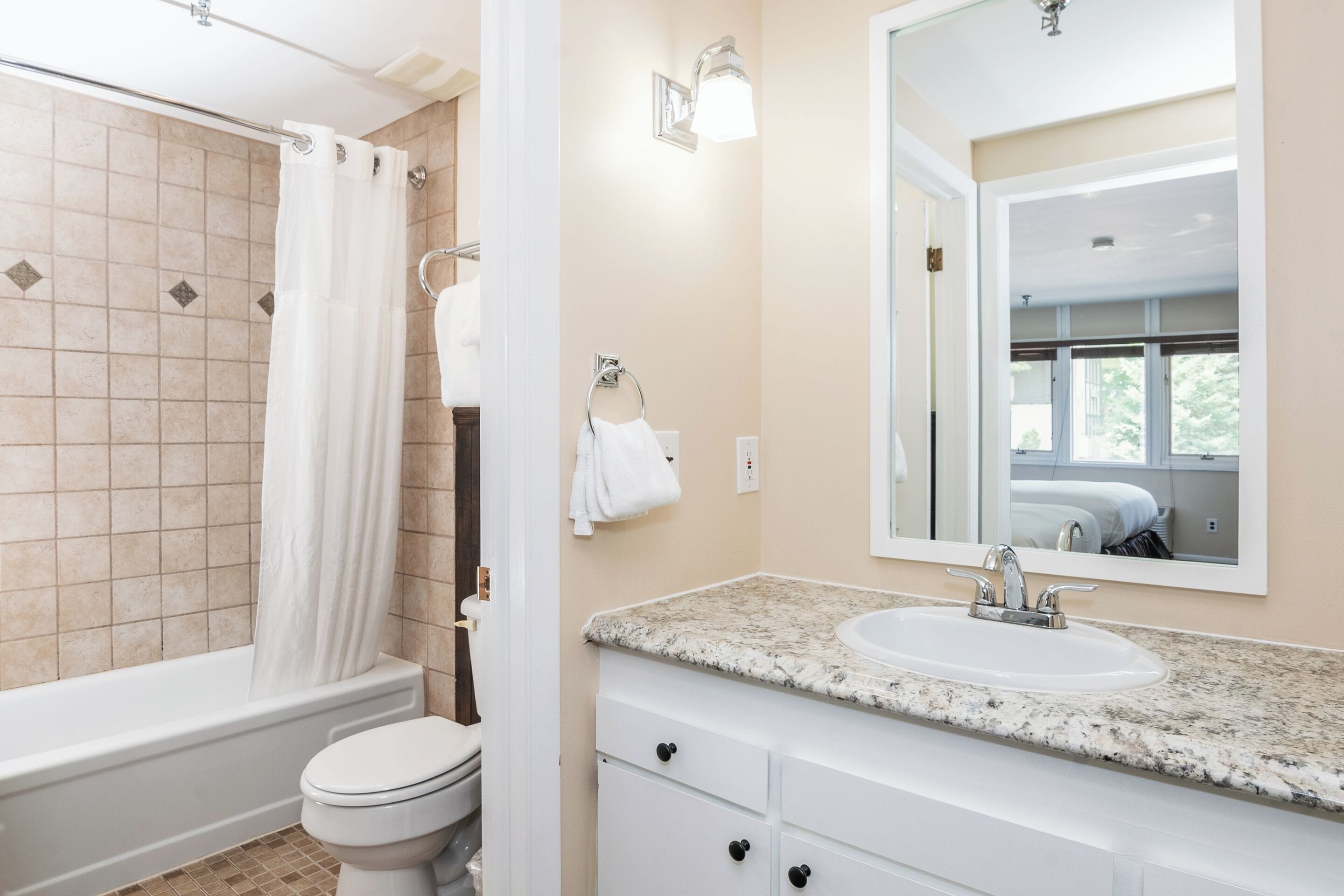 A bathroom with a bathtub, toilet, sink, and mirror.