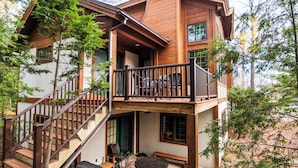 Une maison en bois à plusieurs niveaux, dotée d’un balcon, d’un escalier et d’un espace salon extérieur.