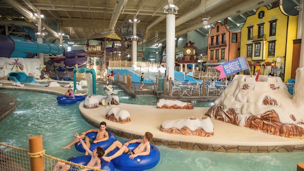 Un parc aquatique intérieur avec des bouées gonflables, des toboggans et un espace de jeux sur le thème d’une montagne enneigée.