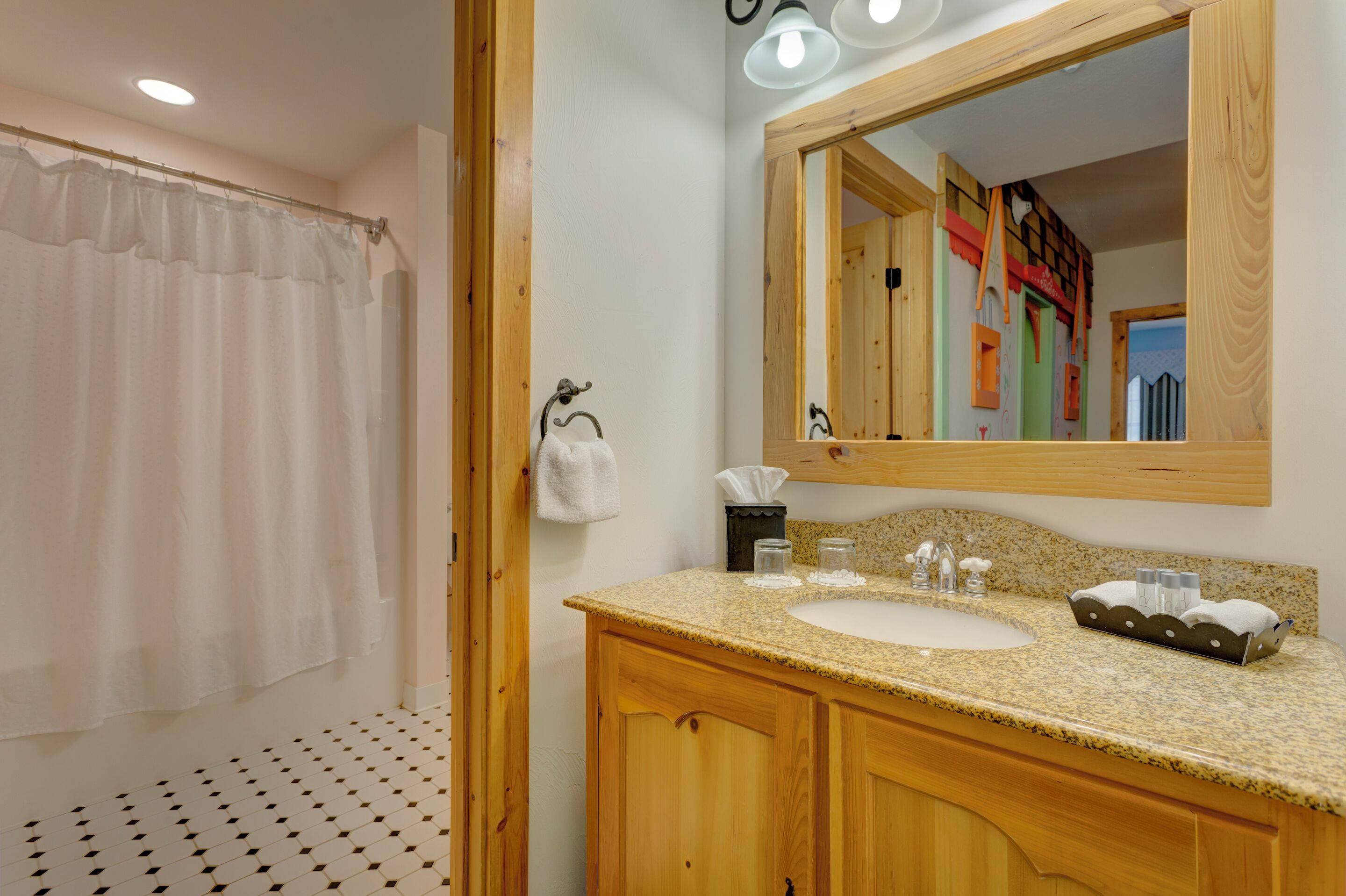 A bathroom with a wooden vanity, a sink, a mirror, and a shower curtain.