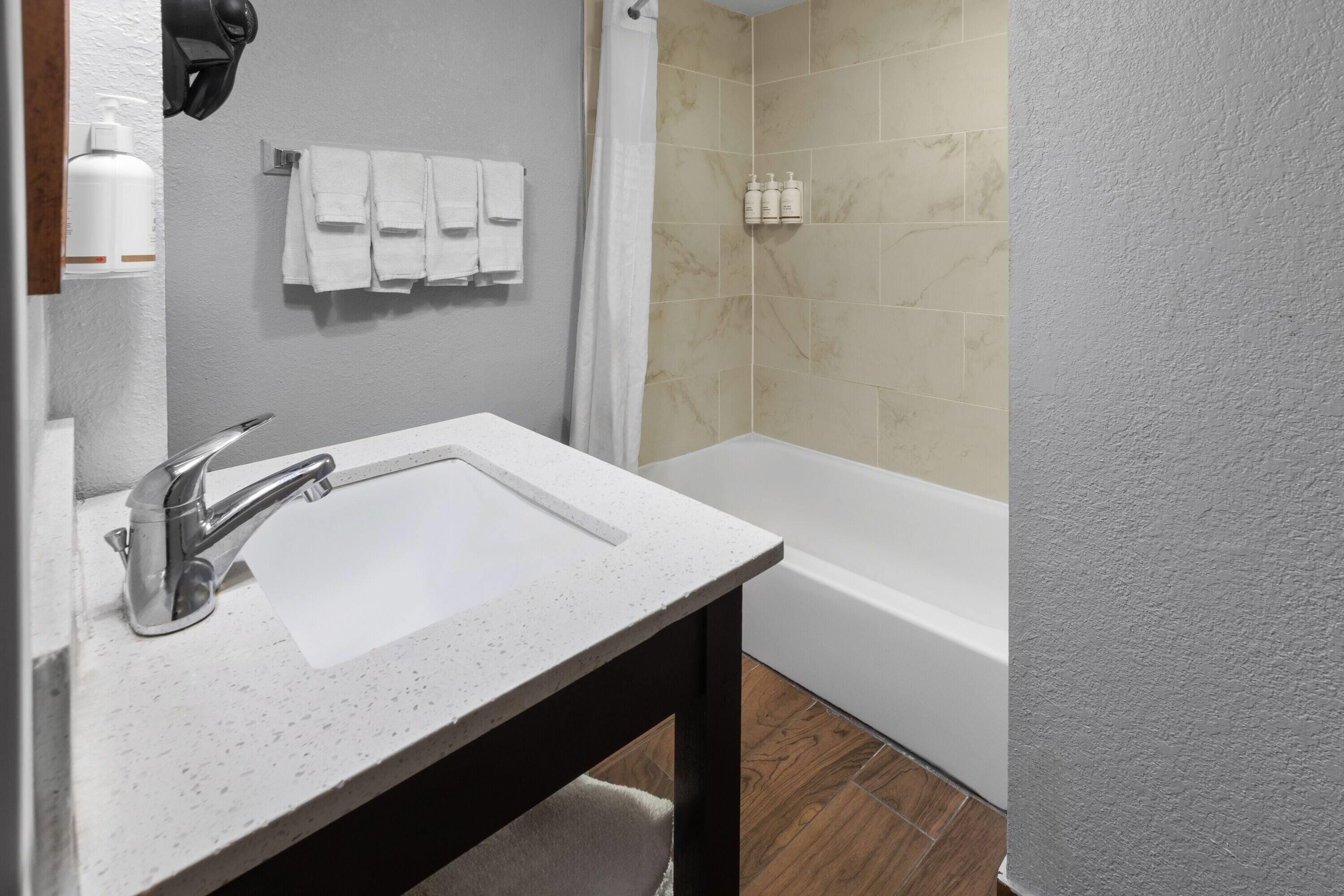 A bathroom with a white sink, a shower curtain, and a bathtub.