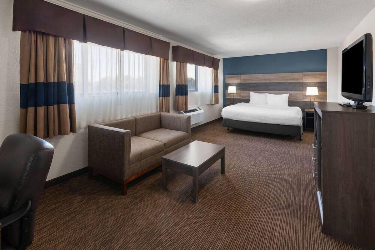 A hotel room with a bed, a sofa, a coffee table, a TV, and a desk.