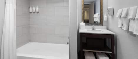 A modern bathroom with a bathtub, a sink, a mirror, and a towel rack.