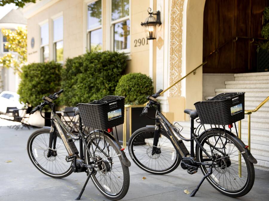 Two bicycles parked on a sidewalk with baskets, in front of a building with the number 2901.